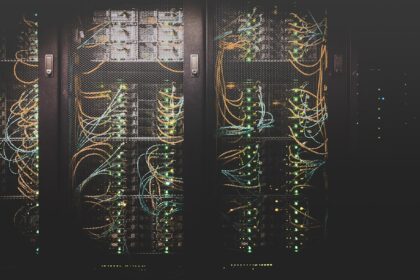 Corredor de servidores com cabos de rede em um centro de dados; imagem ilustrativa da infraestrutura digital.