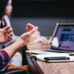 Pessoas reunidas em uma mesa de trabalho com computadores e anotações.