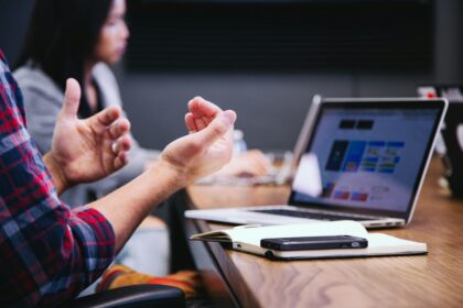 Pessoas reunidas em uma mesa de trabalho com computadores e anotações.